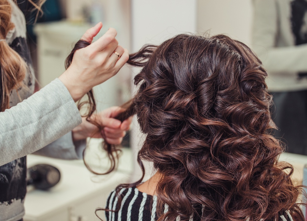 A beautician styling hair in curls.
