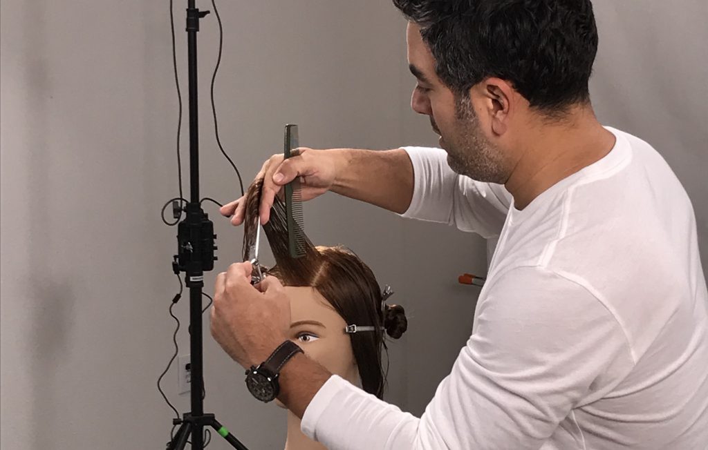 left handed male hairstylist demonstrating how to use left handed scissors on mannequin head