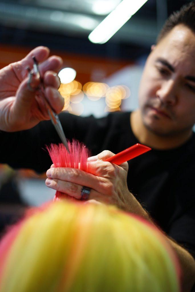 Stylist cutting brightly colored hair.