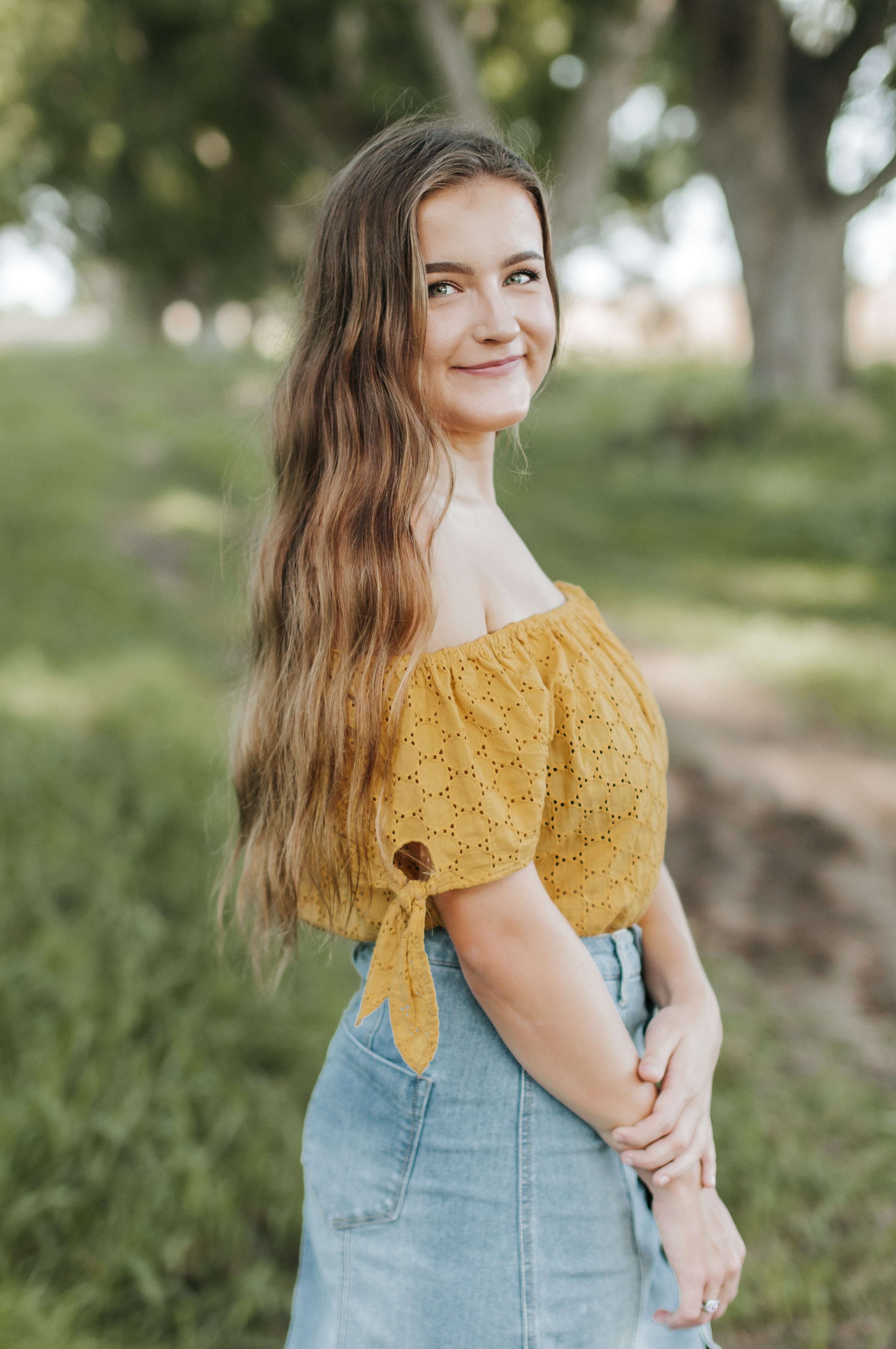 Girl in a summery outfit with long wavy hair.