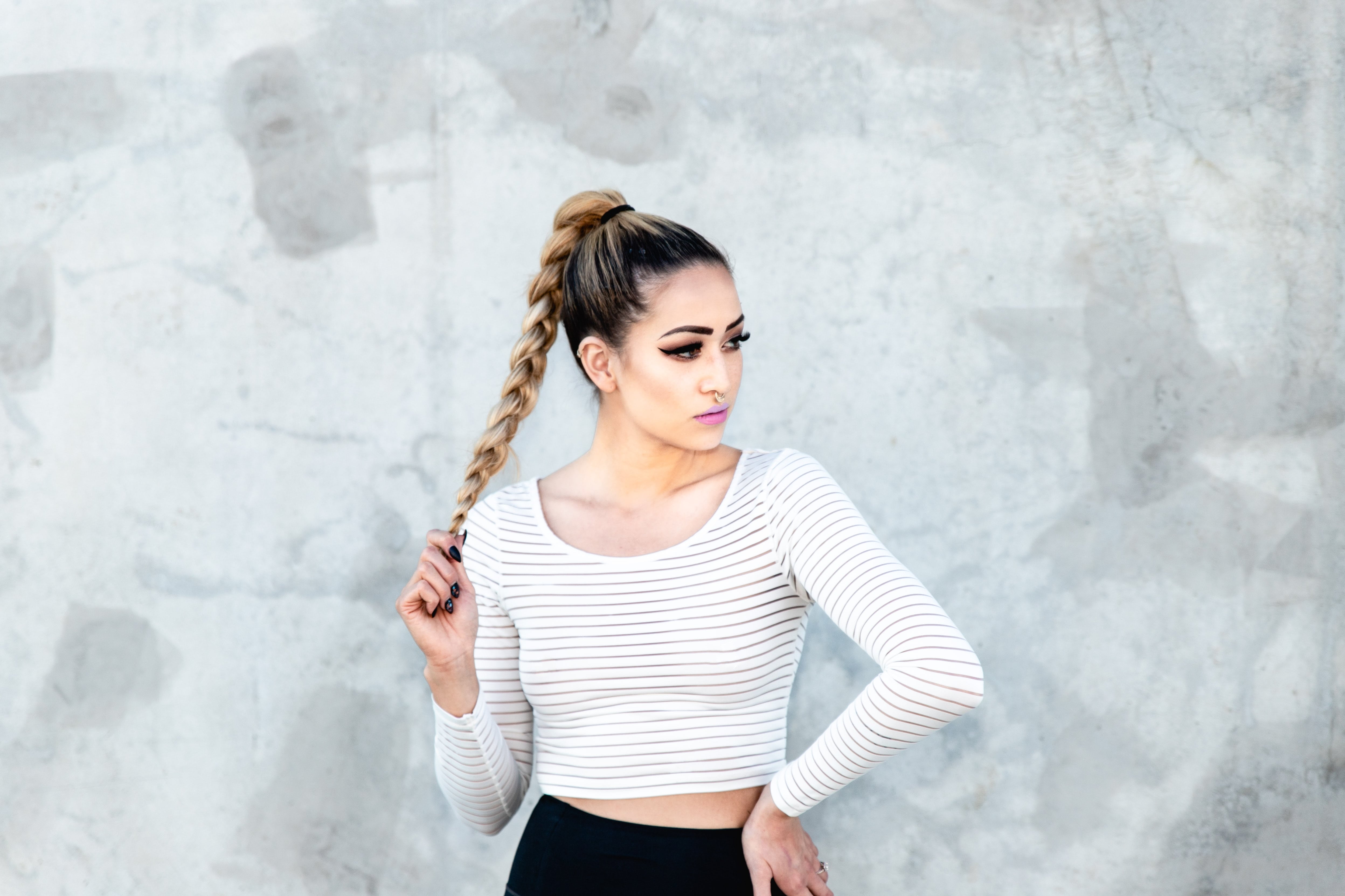 Blonde girl in a white top and black pants with a long braid.