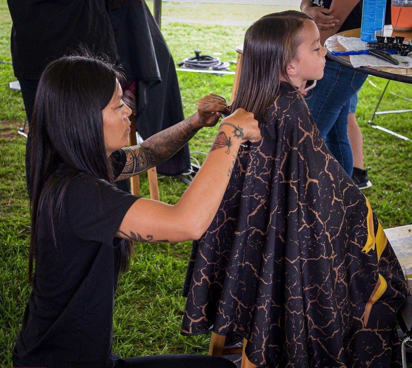 Hairstylist trimming a young girl's hair.
