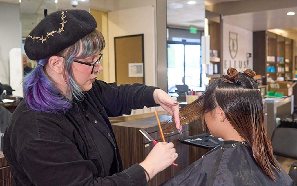 Cosmetology Educator Lorin Hall cuts and colors a model's hair in the Bellus Academy Student Salon and Spa at Bellus Academy in Poway.